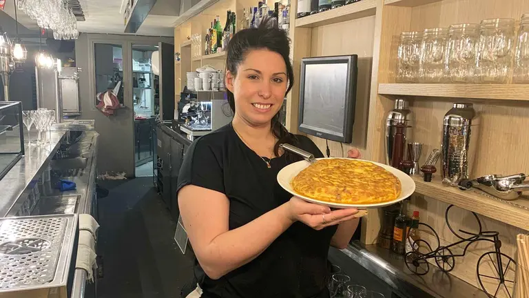 Celia de Pedro sostiene una gran tortilla de patatas en el bar Monasterio de Pamplona. Navarra.com