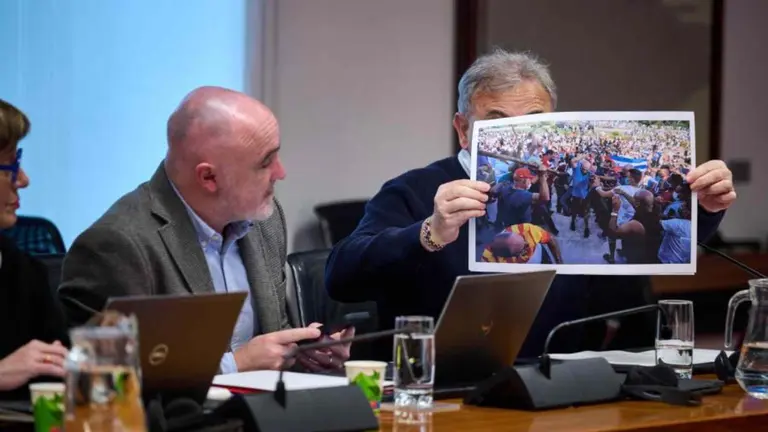 El parlamentario de UPN Pedro Gonz&aacute;lez sostiene una imagen de detenciones de disidentes en Cuba en presencia de Ana Elizalde y Javier Esparza. PARLAMENTO DE NAVARRA