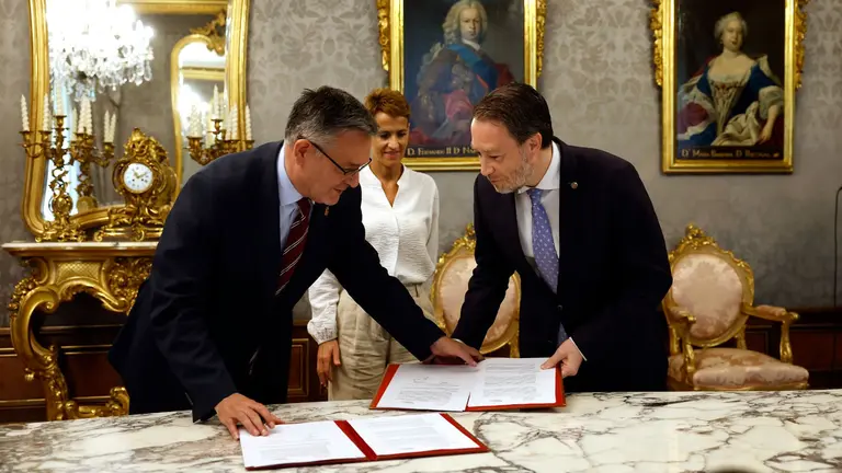 El consejero de Universidad, Innovación y Transformación Digital Juan Luis García Martín (i) y el rector de la UPNA Ramón Gonzalo (d) firman un convenio entre el Ejecutivo y la Universidad Pública de Navarra en un acto celebrado en el Salón Verde del Palacio de Navarra con presencia de la presidenta de la Comunidad Foral María Chivite (c). EFE/ Jesús Diges