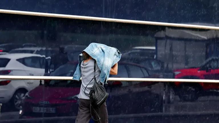 Una mujer se dirige a comprar en medio de una intensa lluvia en una jornada donde la Agencia Estatal de Meteorología (Aemet) ha activado en Navarra aviso amarillo por precipitación acumulada de 15 litros en una hora y tormentas que pueden ir acompañadas de granizo grande y rachas muy fuertes de viento. EFE/ Jesús Diges