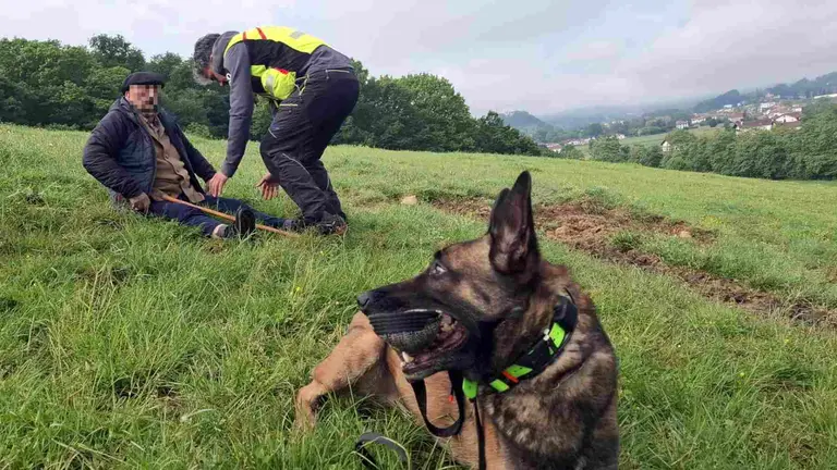 Una agente de la Unidad de Gu&iacute;as Caninos de la Polic&iacute;a Foral junto al hombre en el momento de su localizaci&oacute;n. POLIC&Iacute;A FORAL