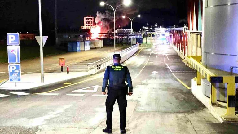 Un agente de la Guardia Civil cierra el paso al pol&iacute;gono en el que se ha producido el incendio. GUARDIA CIVIL