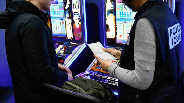 Un agente de la polic&iacute;a Foral comprueba la documentaci&oacute;n de las m&aacute;quinas de azar en un establecimiento de Pamplona. POLIC&Iacute;A FORAL