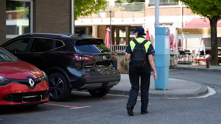 Una operaria de Dornier revisa los coches estacionados en la zona azul de Pamplona. IÑIGO ALZUGARAY