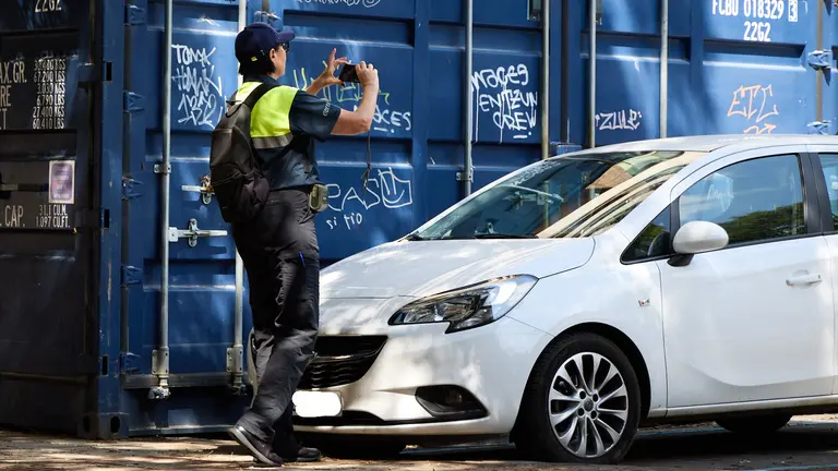 Una operaria de Dornier fotografía  un coche sin ticket de aparcamiento  en la zona azul de Pamplona. IÑIGO ALZUGARAY