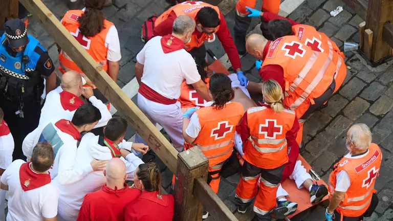 Un mozo es atendido por los servicios médicos de la Cruz Roja tras el cuarto encierro de San Fermín 2025 con toros de la ganadería de Victoriano del Río en el tramo de Mercaderes. IÑIGO ALZUGARAY