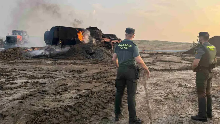 Dos agentes de la Guardia Civil ante la m&aacute;quina incendiada en la planta de reciclaje. GUARDIA CIVIL