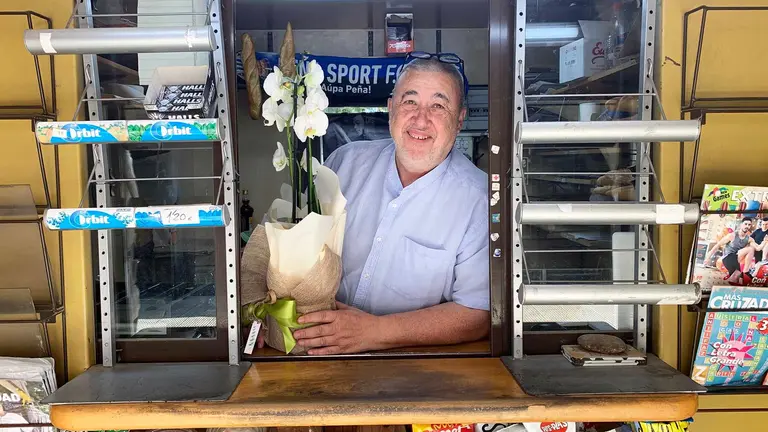 Javier Inchauspe sostiene una flor regalada el último día de trabajo en su kiosko de Tafalla. Navarra.com