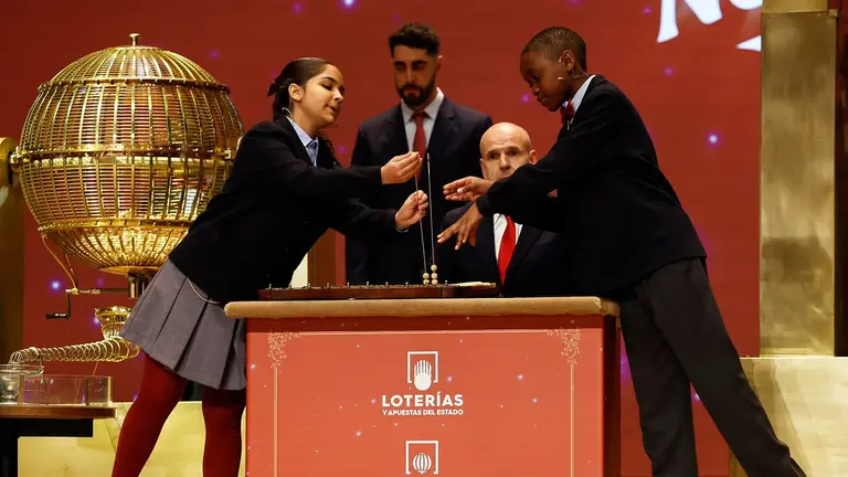 Samanta Fuster (i) y &Aacute;ngel Abaga (d), los ni&ntilde;os de la Residencia San Ildefonso del Ayuntamiento de Madrid encargados de cantar premio y n&uacute;mero, respectivamente, de la primera tabla de del Sorteo Extraordinario de Navidad celebrado este lunes en el Teatro Real de Madrid. EFE/Chema Moya
