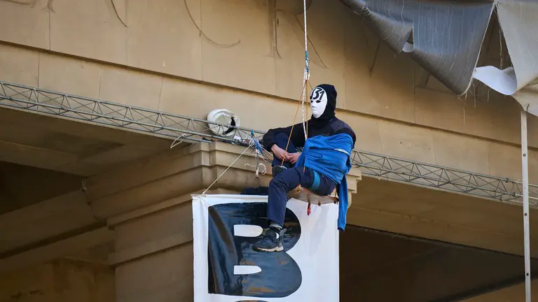 Dos personas se cuelgan del monumento a Los Ca&iacute;dos de Pamplona en la Plaza de la Libertad. PABLO LASAOSA