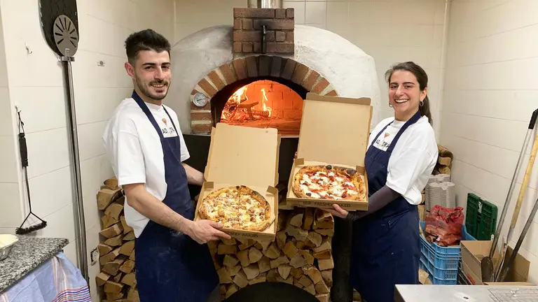 Matteo y Alessia sostienen dos pizzas junto a su horno de le&ntilde;a en Pamplona. Navarra.com