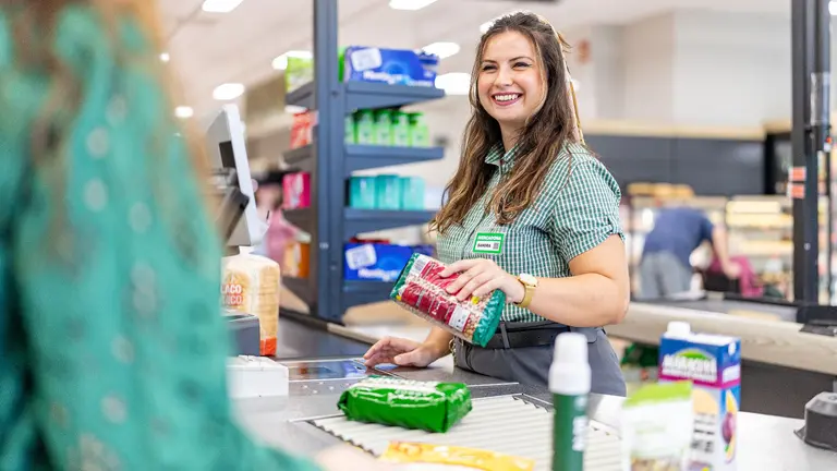 Una trabajadora de Mercadona sonr&iacute;e a un cliente en caja. CEDIDA