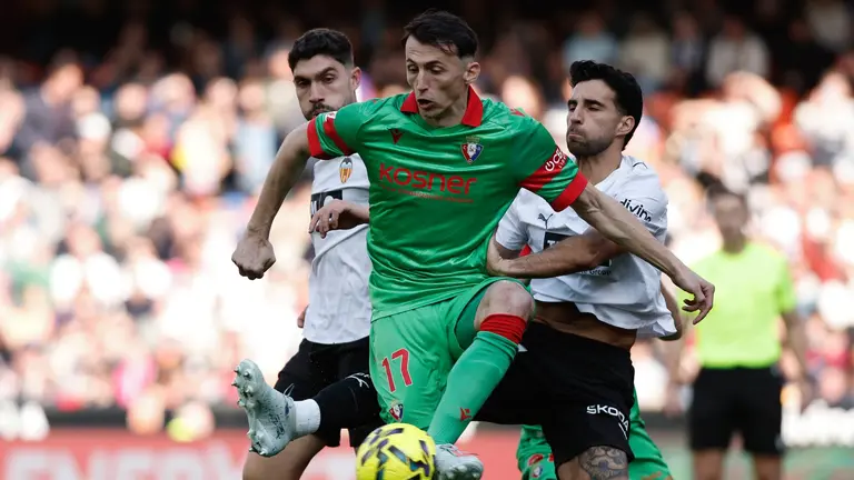 Ante Budimir pelea ante dos rivales por controlar el bal&oacute;n ante el Valencia en Mestalla. EFE.