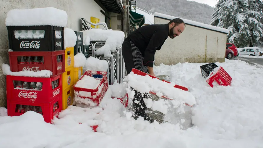 Un hombre retira la nieve acumulada a la entrada de su restaurante en Roncesvalles, (Navarra), localidad que hoy ha amanecido nevada debido a la progresiva bajada de la cota de nieve, que ha hecho que durante la noche se movilicen máquinas quitanieves de forma preventiva. EFE/VILLAR LÓPEZ