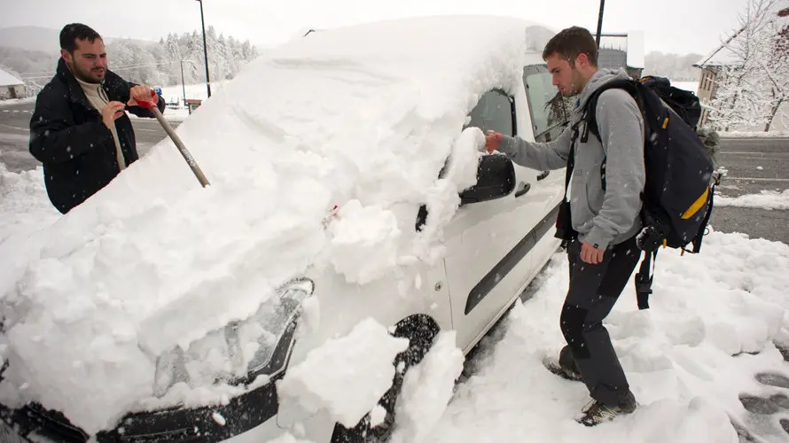 Dos peregrinos de Barcelona que realizan el Camino de Santiago retiran la nieve acumulada en un vehículo en Roncesvalles (Navarra), localidad que hoy ha amanecido nevada debido a la progresiva bajada de la cota de nieve, que ha hecho que durante la noche se movilicen máquinas quitanieves de forma preventiva. EFE/Villar López