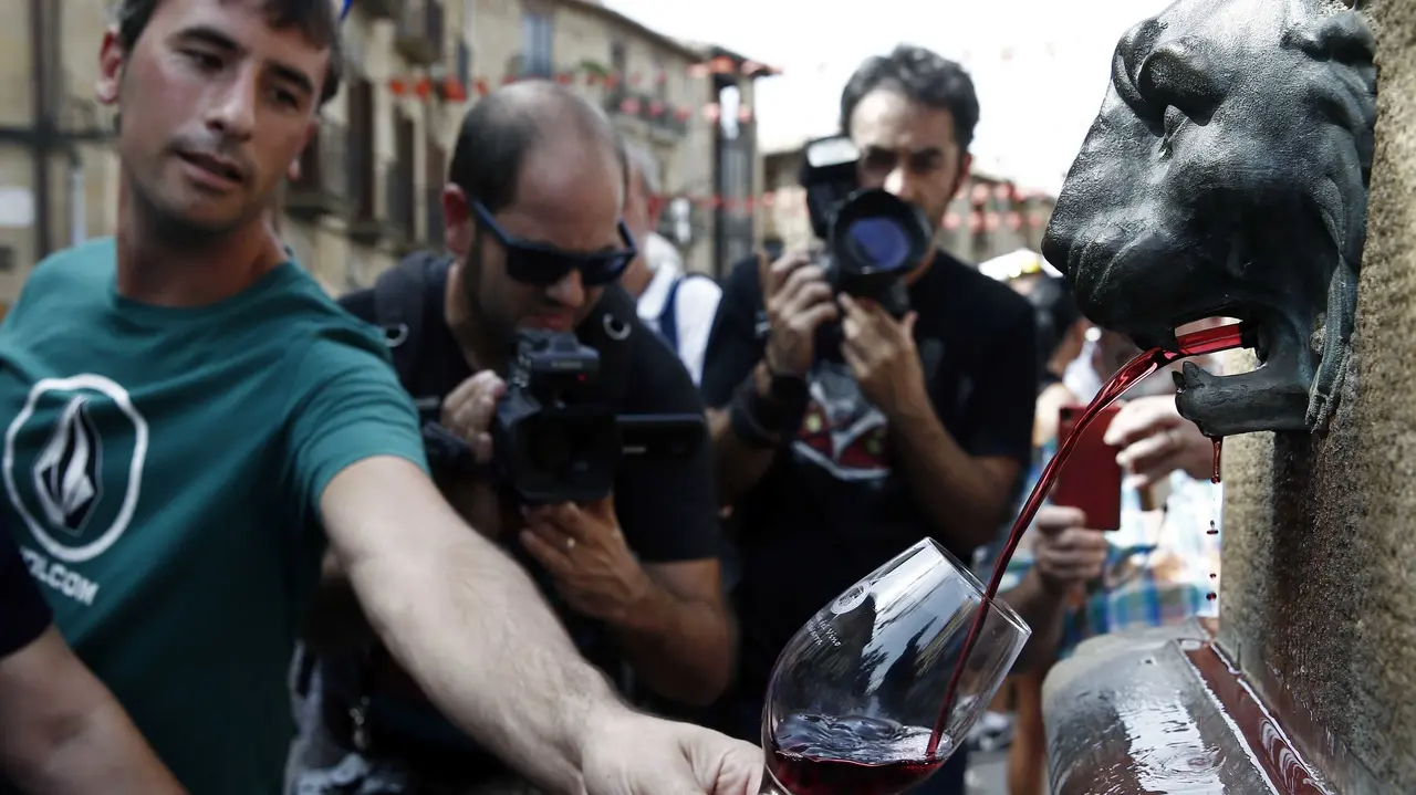 GRA165. OLITE (NAVARRA), 04/09/2016.- Una persona llena su copa de la fuente que preside la plaza Carlos III de Olite de la que brota vino tinto y rosado del año, en vez de agua, en una jornada en la que dicha localidad navarra acoge hoy la XXVI Fiesta de la Vendimia, marcada por un descenso de la producción y la ausencia de precipitaciones durante el verano, que hace que el estado sanitario de la uva sea "excepcional". EFE/Jesús Diges