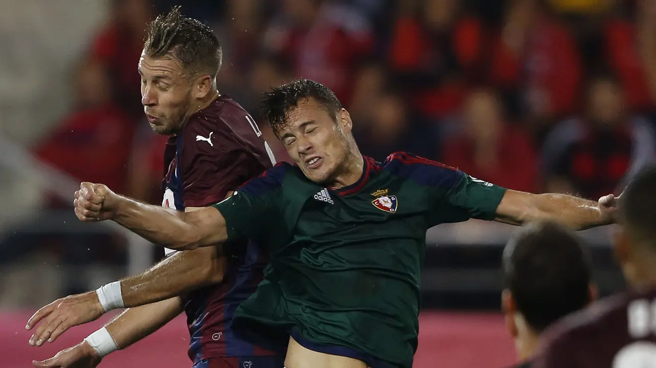 El defensa francés Florian Lejuene (i) despeja el balón ante la presencia del delantero del Osasuna, Oriol Riera (d) durante el encuentro de la octava jornada de Liga en Primera División que se disputa en el estadio de Ipurúa de la localidad guipuzcoana de Eibar. EFE/Javier Etxezarreta.