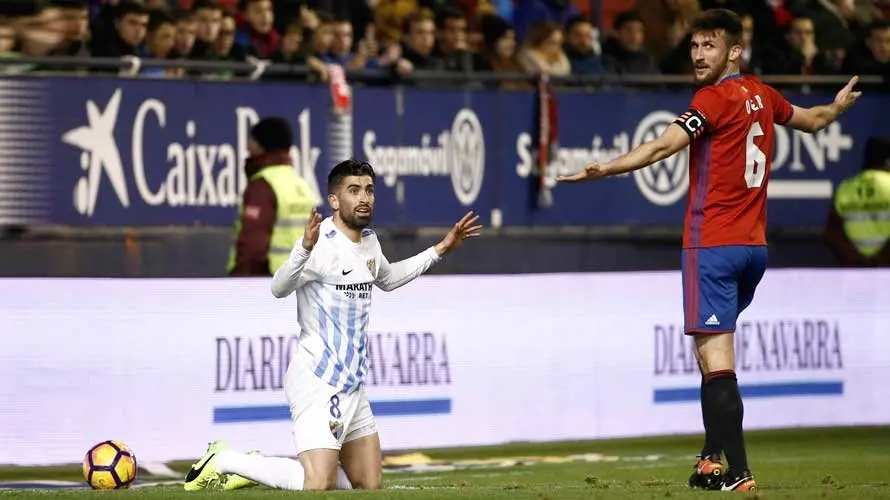 El delantero uruguayo del Málaga Michael Santos (i) ante el defensa del Osasuna Oier Sanjurjo durante el partido de la vigésima jornada de Liga que disputan en el estadio El Sadar de Pamplona. EFE/Jesus Diges