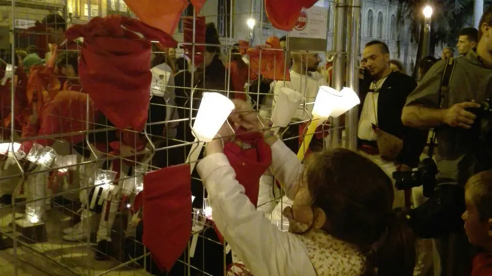 Una niña coloca un pañuelico a las puertas de San Lorenzo, donde se encuentra la capilla de San Fermín, durante el Pobre de mí. ESCALADA