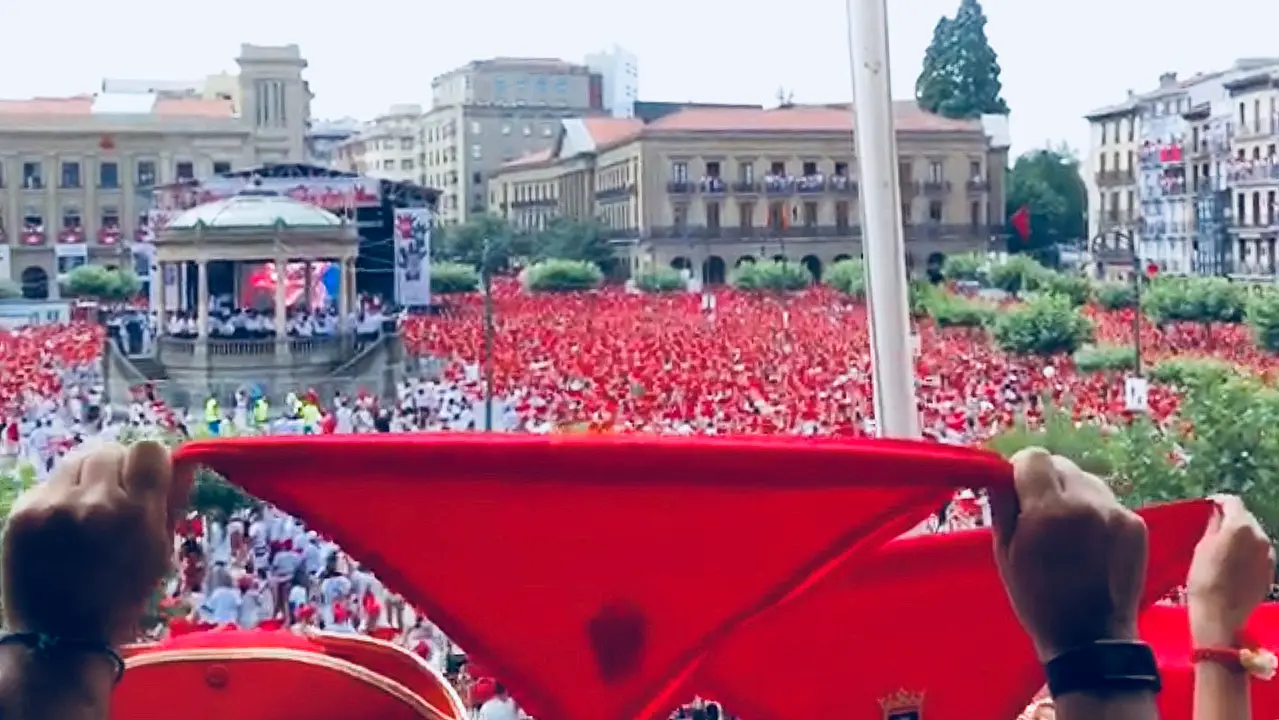 Varias personas ondean sus pañuelos desde la Plaza del Castillo de Pamplona en el Casino Principal