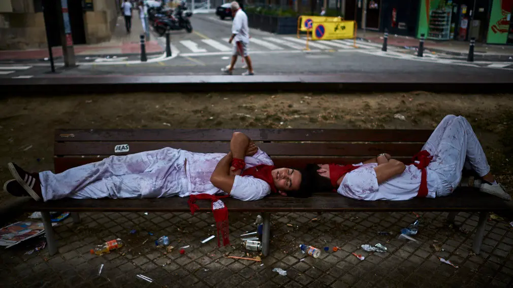 Dos jovenes duermen en los bancos del paseo sarasate tras el primer encierro de San Fermin. MIGUEL OSÉS
