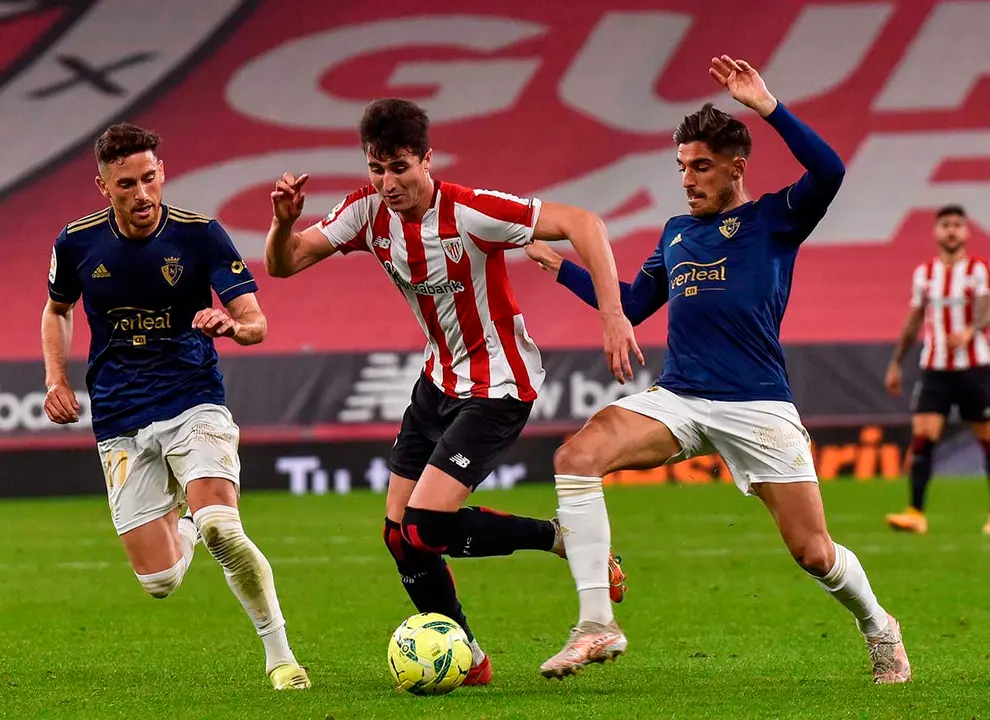 BILBAO, 08/05/2021.- El delantero del Athletic Club, Jon Morcillo (c), intenta llevarse el balón ante los jugadores de Osasuna, Jon Moncayola (d) y Kike Barja, durante el encuentro correspondiente a la jornada 35 de primera división que disputan hoy sábado en el estadio de San Mamés, en Bilbao. EFE/Miguel Toña.