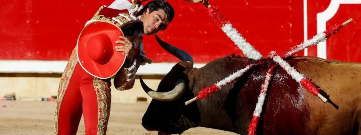 El diestro Jesús Enrique Colombo coloca unas banderillas con una sombrero en la mano durante la lidia del tercer toro de la tarde en la sexta de abono de la Feria del Toro de los Sanfermines 2022 REUTERS  Juan Medina