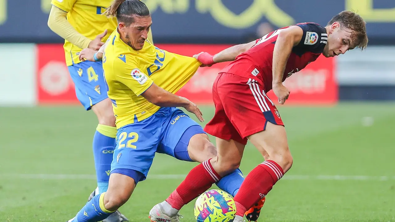 El defensa del Cádiz Luis Espino (i) es agarrado por Pablo Ibáñez, de Osasuna, durante el partido de Liga que enfrenta al Cádiz CF y al Club Atlético Osasuna este martes en el estadio Nuevo Mirandilla. EFE/Román Ríos