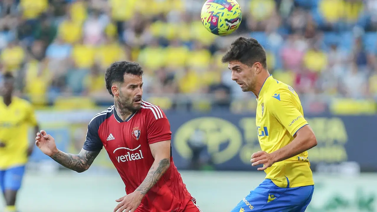 El centrocampista del Cádiz Rubén Sobrino (d) cabecea un balón ante Rubén García, de Osasuna, durante el partido de Liga que enfrenta al Cádiz CF y al Club Atlético Osasuna este martes en el estadio Nuevo Mirandilla. EFE/Román Ríos