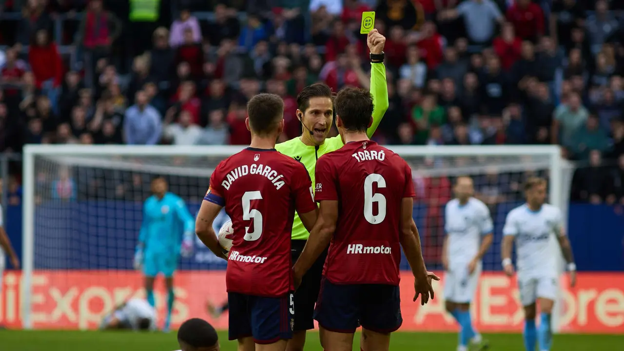 José Luis Munuera Montero (árbitro del partido) muestra una tarjeta amarilla a Lucas Torró (6. CA Osasuna) durante el partido de La Liga EA Sports entre CA Osasuna y Girona FC disputado en el estadio de El Sadar en Pamplona. IÑIGO ALZUGARAY