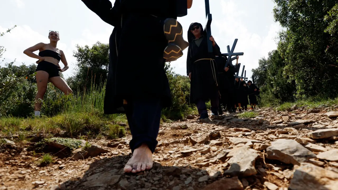 Penitentes de la hermandad de Los Cruceros vestidos con túnicas negras portan pesadas cruces de madera y caminan hasta la ermita de la Trinidad, a 740 metros de altitud. Esta romería penitencial se celebra desde el siglo XIX el dia de la Santísima Trinidad, el primer domingo después de Pentecostés. EFE / Jesús Diges