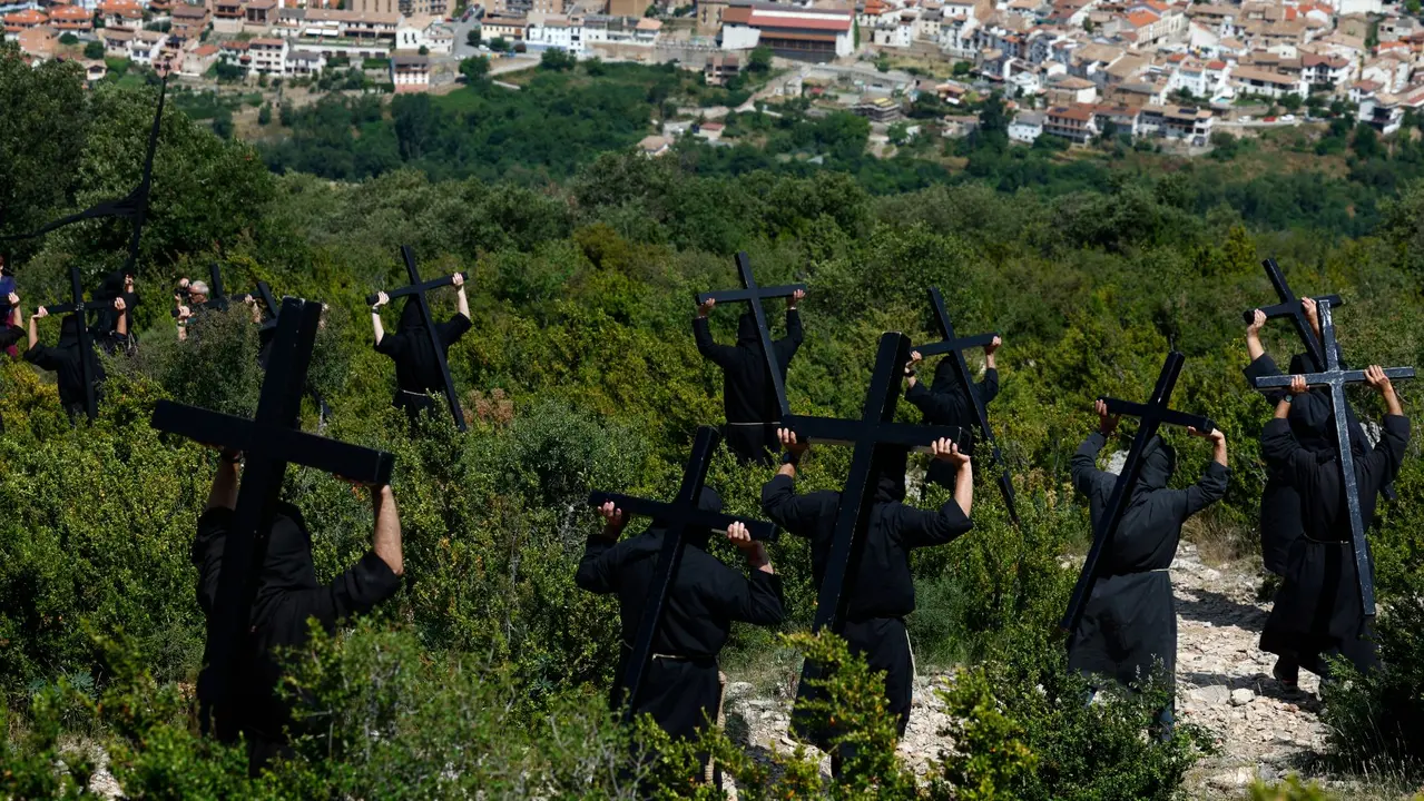 Penitentes de la hermandad de Los Cruceros vestidos con túnicas negras portan pesadas cruces de madera y caminan hasta la ermita de la Trinidad, a 740 metros de altitud. Esta romería penitencial se celebra desde el siglo XIX el dia de la Santísima Trinidad, el primer domingo después de Pentecostés. EFE / Jesús Diges