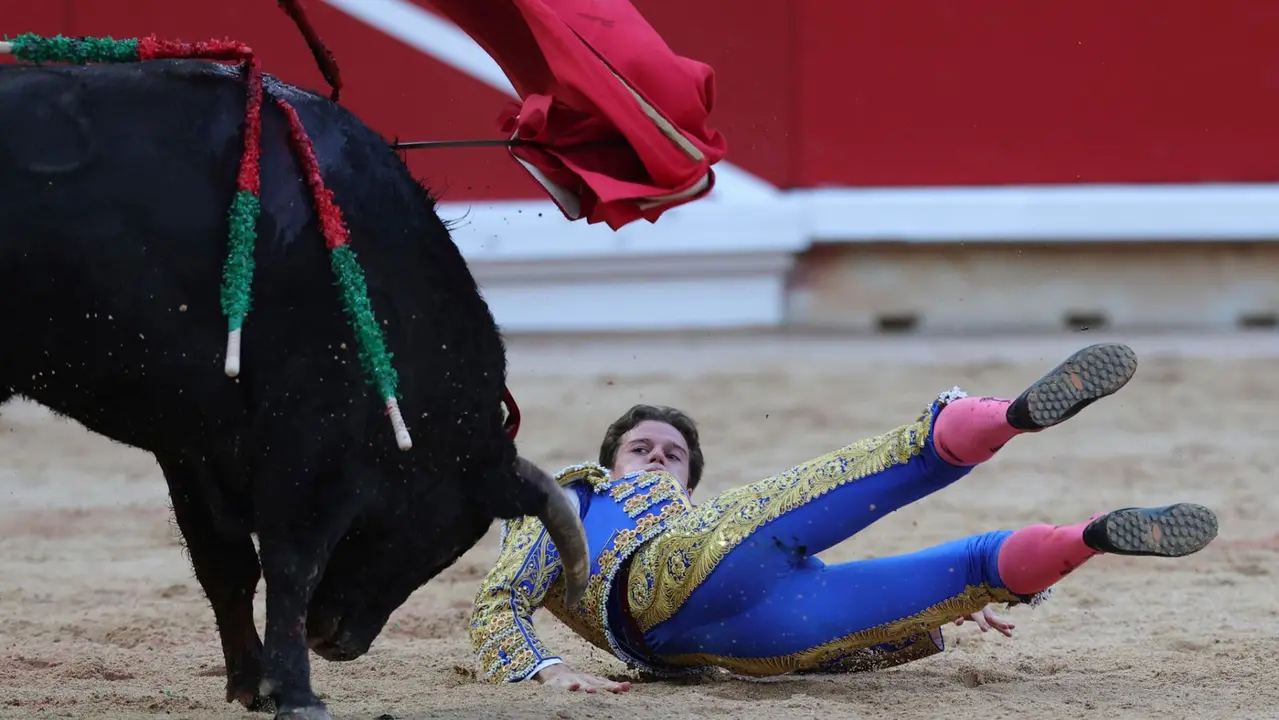 El novillero Bruno Martínez revolcado en su faena al primero de su lote durante la novillada que con motivo de la Feria del Toro de los Sanfermines 2025 se celebra hoy sábado en la Plaza de Toros de Pamplona. EFE/ J.P Urdiroz