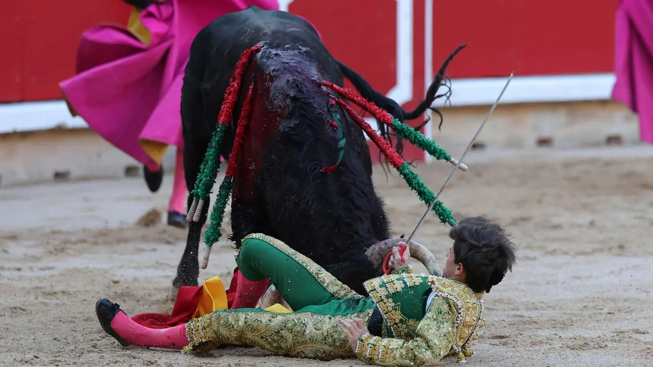 El novillero Aaron Palacio es revolcado por el primero de su lote durante la novillada que con motivo de la Feria del Toro de los Sanfermines 2025 se celebra hoy sábado en la Plaza de Toros de Pamplona, compartiendo cartel con Iker Fernández ´El Mene´ y Bruno Martínez, lidiando reses de la ganadería Pincha, de la localidad navarra de Lodosa. EFE/ J.P Urdiroz