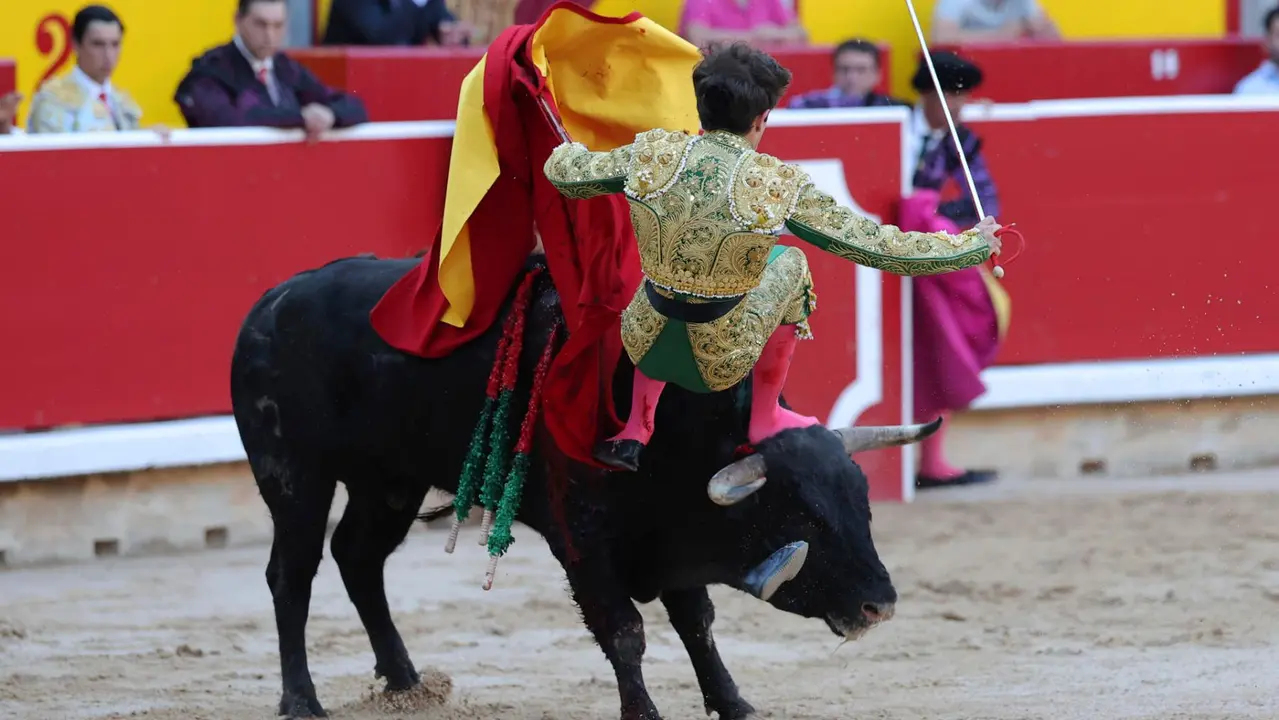 El novillero Aaron Palacio es revolcado por el primero de su lote durante la novillada que con motivo de la Feria del Toro de los Sanfermines 2025 se celebra hoy sábado en la Plaza de Toros de Pamplona, compartiendo cartel con Iker Fernández ´El Mene´ y Bruno Martínez, lidiando reses de la ganadería Pincha, de la localidad navarra de Lodosa. EFE/ J.P Urdiroz