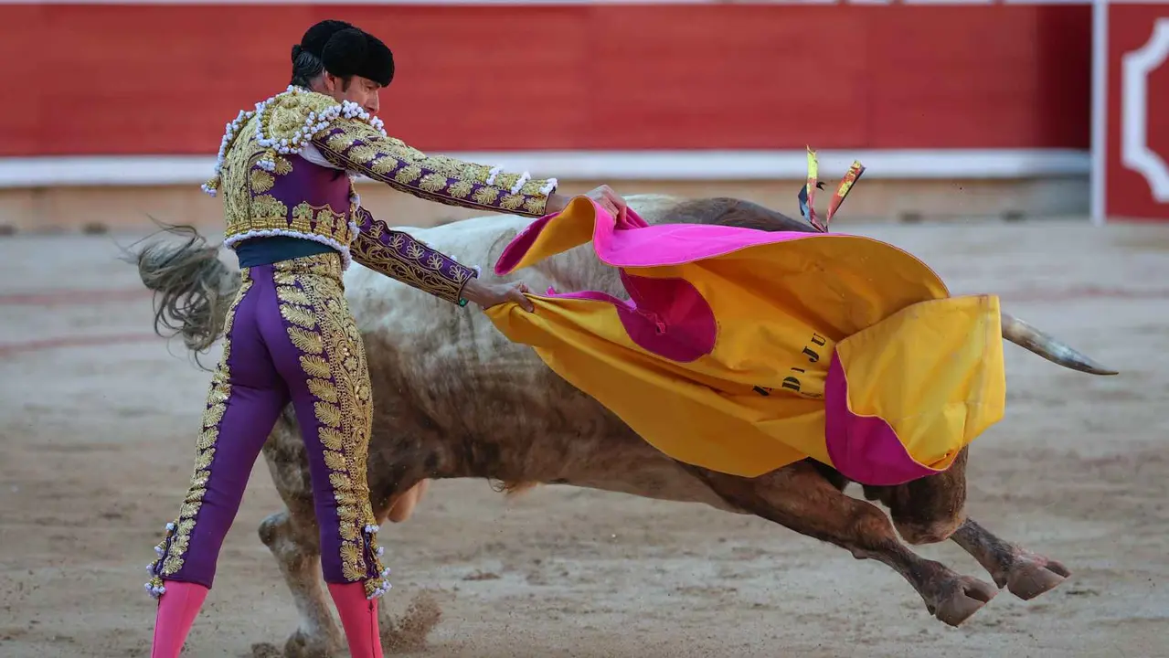 El torero Emilio de Justo recibe con el capote a su primer toro de la tarde en la sexta de abono de la Feria de Toro de los Sanfermines 2025 con toros de la ganadería madrileña de Victoriano del Río Cortés y en la que comparte cartel con los diestros Sebastián Castella y Borja Jiménez. EFE/J.P. Urdíroz