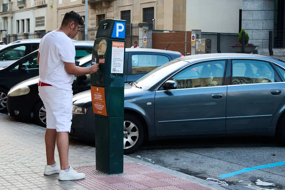 Un joven paga la zona azul durante las fiestas de San Fermín 2025. IÑIGO ALZUGARAY