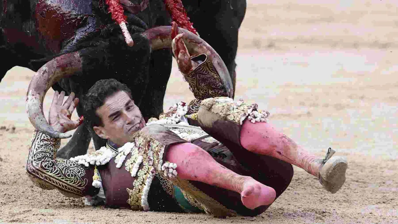 El torero Fernando Adrián sufre un revolcón durante la lidia a su segundo toro de la tarde en la novena de abono de la Feria de Toro de los Sanfermines 2025 con toros de la ganadería gaditana La Palmosilla y en la que comparte cartel con los diestros Jiménez Fortes y Ginés Marín. EFE/Jesús Diges