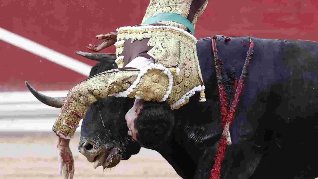 El torero Fernando Adrián sufre un revolcón durante la lidia a su segundo toro de la tarde en la novena de abono de la Feria de Toro de los Sanfermines 2025 con toros de la ganadería gaditana La Palmosilla y en la que comparte cartel con los diestros Jiménez Fortes y Ginés Marín. EFE/Jesús Diges