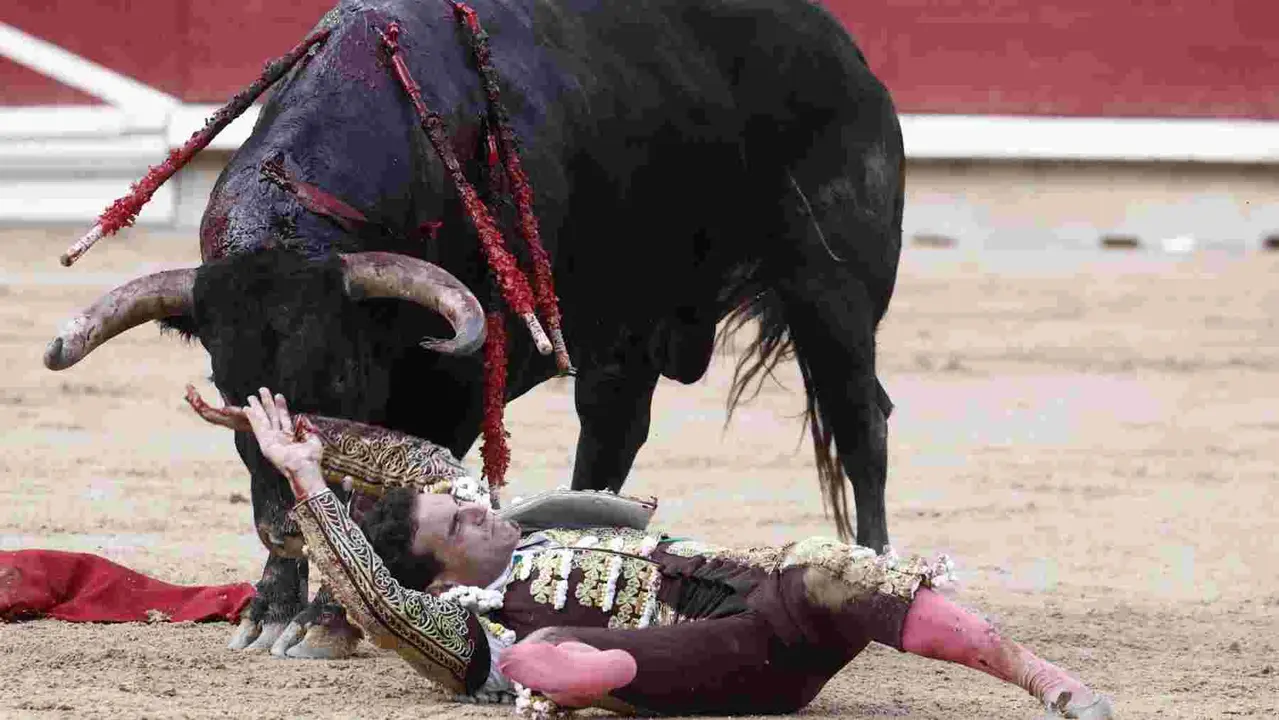 El torero Fernando Adrián sufre un revolcón durante la lidia a su segundo toro de la tarde en la novena de abono de la Feria de Toro de los Sanfermines 2025 con toros de la ganadería gaditana La Palmosilla y en la que comparte cartel con los diestros Jiménez Fortes y Ginés Marín. EFE/Jesús Diges