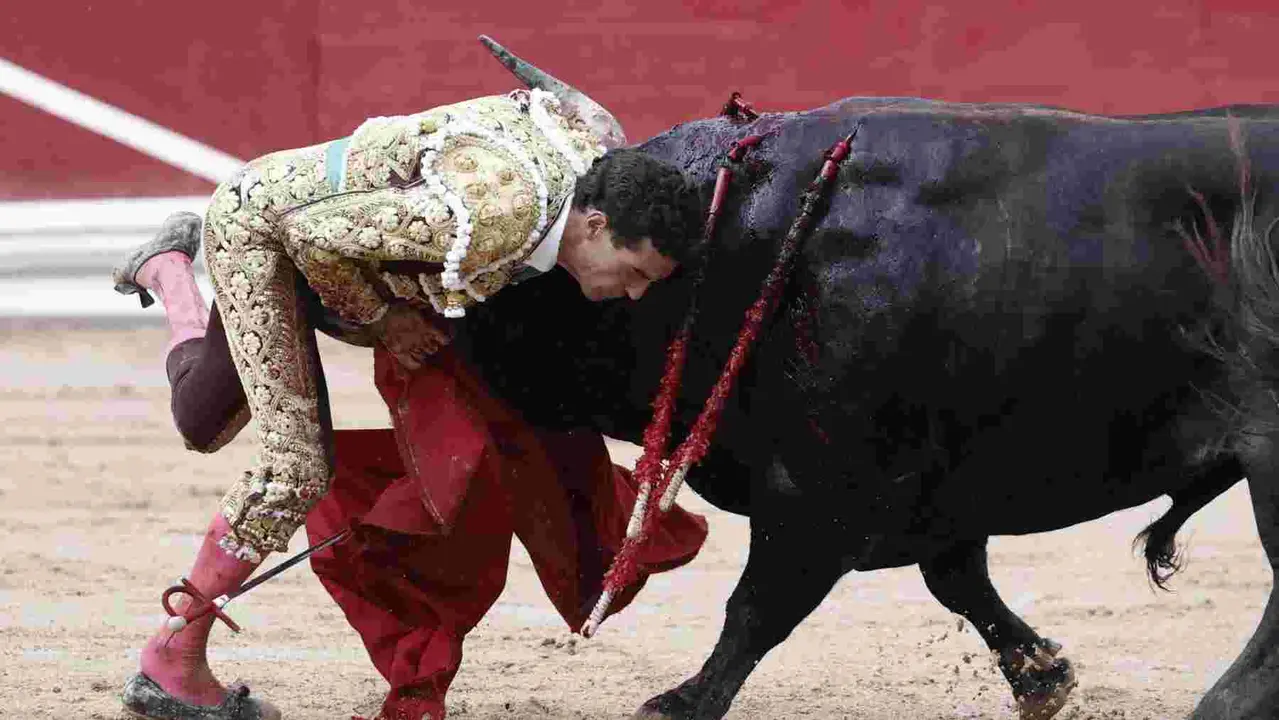 El torero Fernando Adrián sufre un revolcón durante la lidia a su segundo toro de la tarde en la novena de abono de la Feria de Toro de los Sanfermines 2025 con toros de la ganadería gaditana La Palmosilla y en la que comparte cartel con los diestros Jiménez Fortes y Ginés Marín. EFE/Jesús Diges