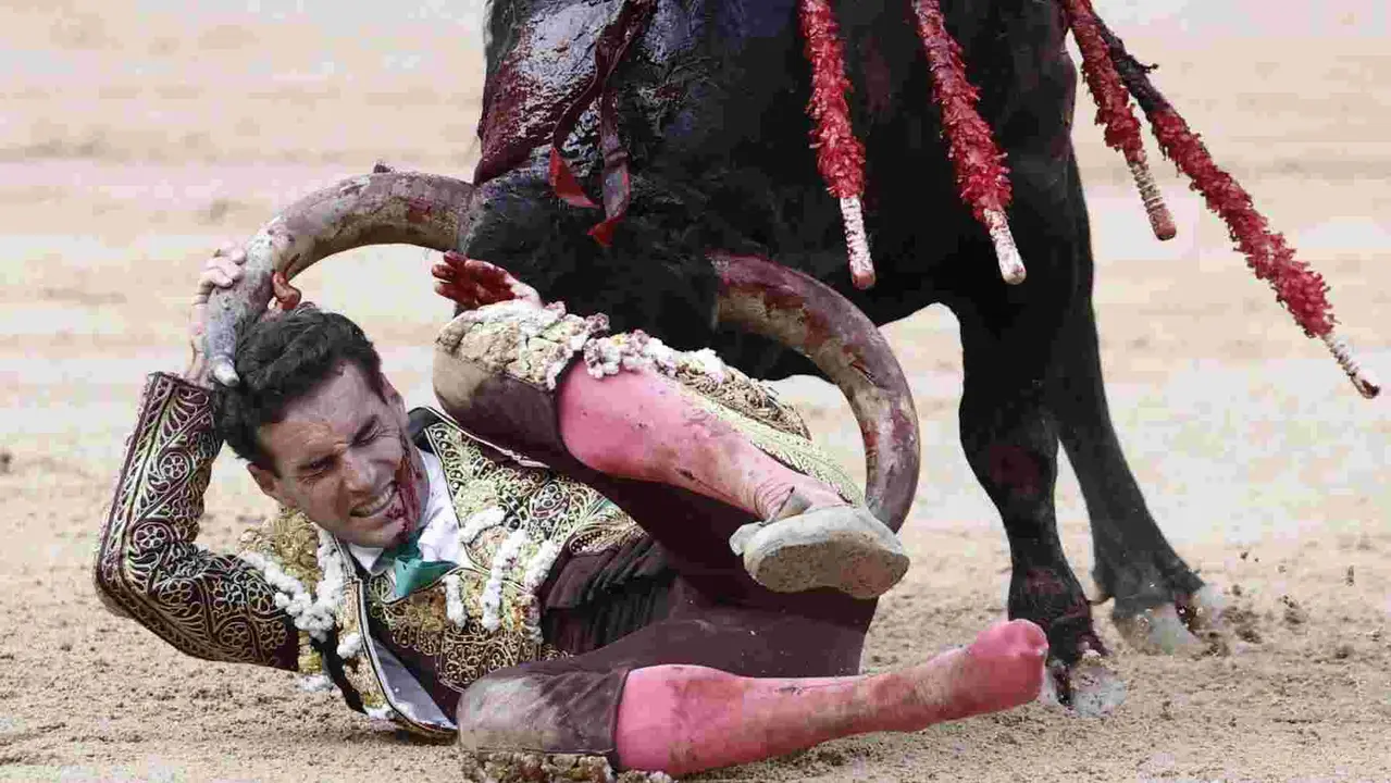 El torero Fernando Adrián sufre un revolcón durante la lidia a su segundo toro de la tarde en la novena de abono de la Feria de Toro de los Sanfermines 2025 con toros de la ganadería gaditana La Palmosilla y en la que comparte cartel con los diestros Jiménez Fortes y Ginés Marín. EFE/Jesús Diges