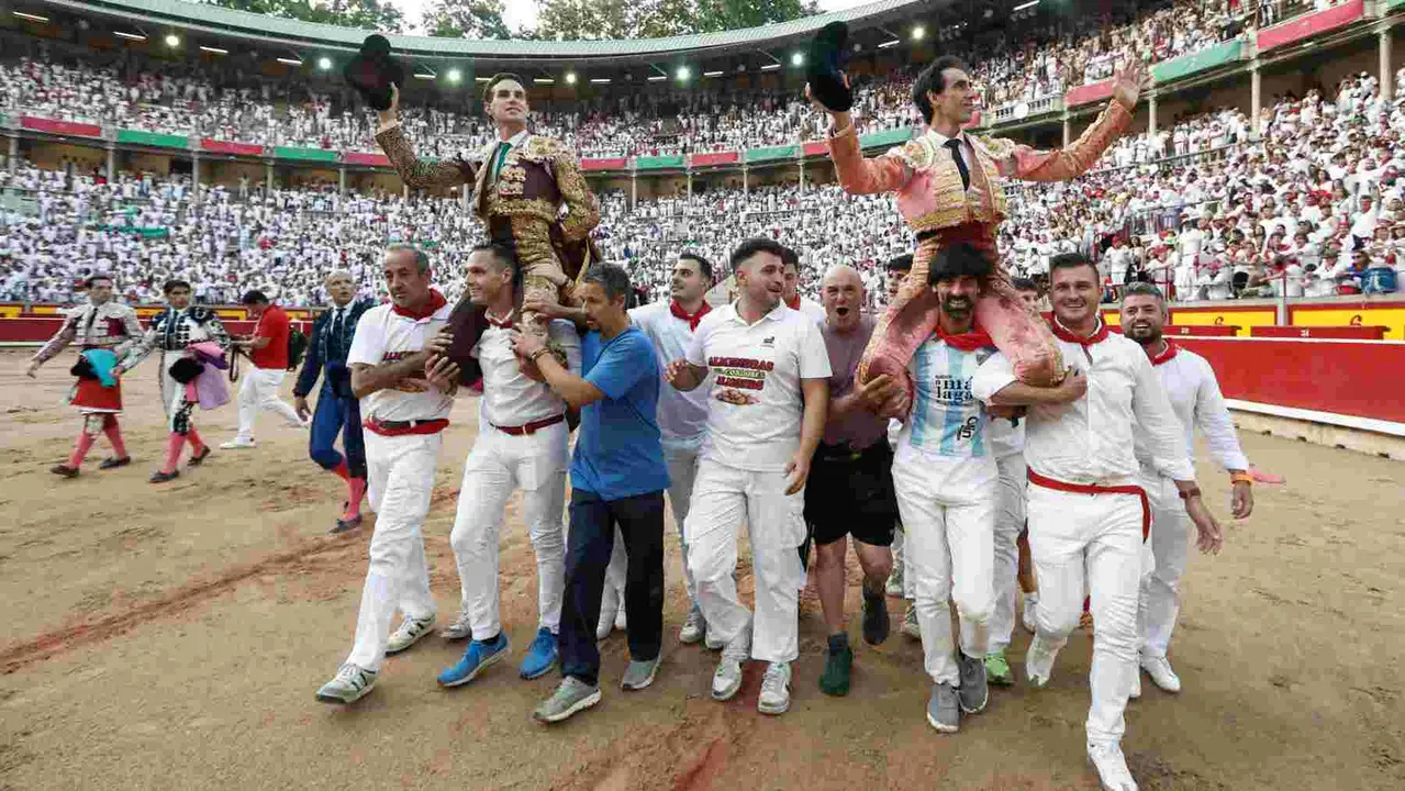 Los diestros Fernando Adrián (i) y Jiménez Fortes salen a hombros a la finalización de la novena corrida de abono de la Feria de Toro de los Sanfermines 2025 que se ha celebrado hoy domingo en la plaza de toros de Pamplona. EFE/Jesús Diges