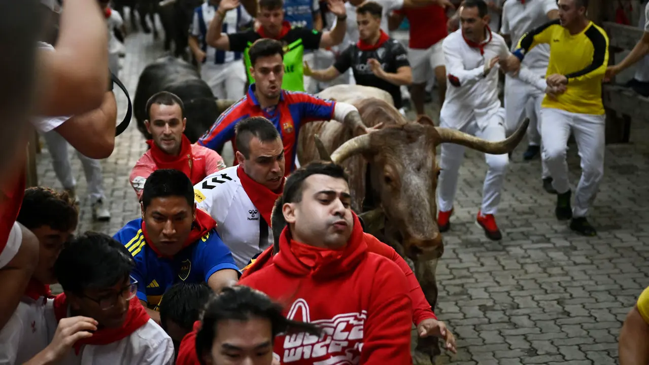 Octavo y último encierro de San Fermín 2025 con toros de Miura en la bajada al callejón. PABLO LASAOSA