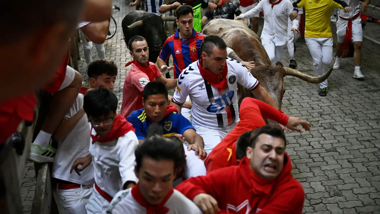 Octavo y último encierro de San Fermín 2025 con toros de Miura en la bajada al callejón. PABLO LASAOSA