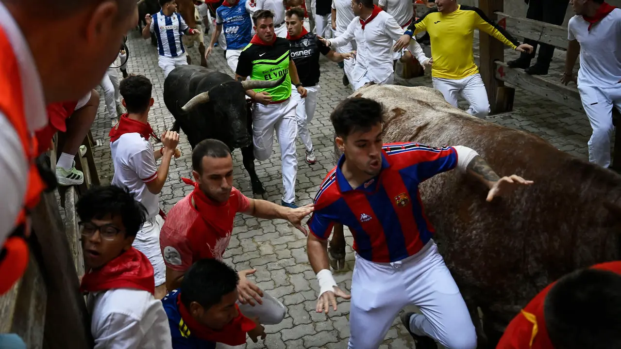 Octavo y último encierro de San Fermín 2025 con toros de Miura en la bajada al callejón. PABLO LASAOSA