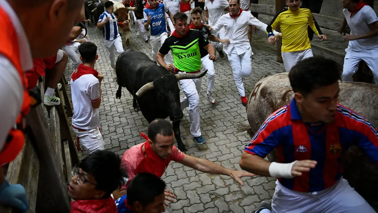 Octavo y último encierro de San Fermín 2025 con toros de Miura en la bajada al callejón. PABLO LASAOSA