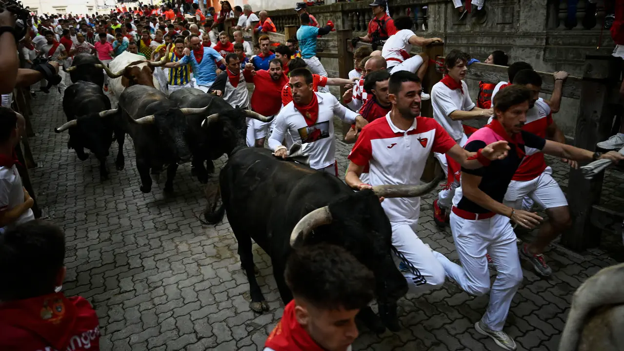 Octavo y último encierro de San Fermín 2025 con toros de Miura en la bajada al callejón. PABLO LASAOSA