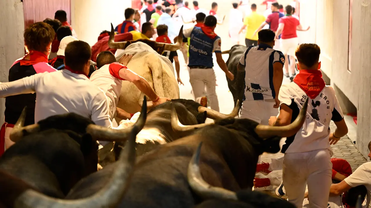 Octavo y último encierro de San Fermín 2025 con toros de Miura en la bajada al callejón. PABLO LASAOSA