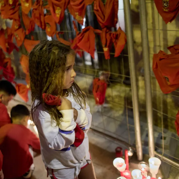 Cientos de personas depositan sus velas y pañuelos frente a la Iglesia de San Lorenzo momentos después del Pobre de mí con el que finalizan los nueve días de las Fiestas de San Fermín 2025. IÑIGO ALZUGARAY